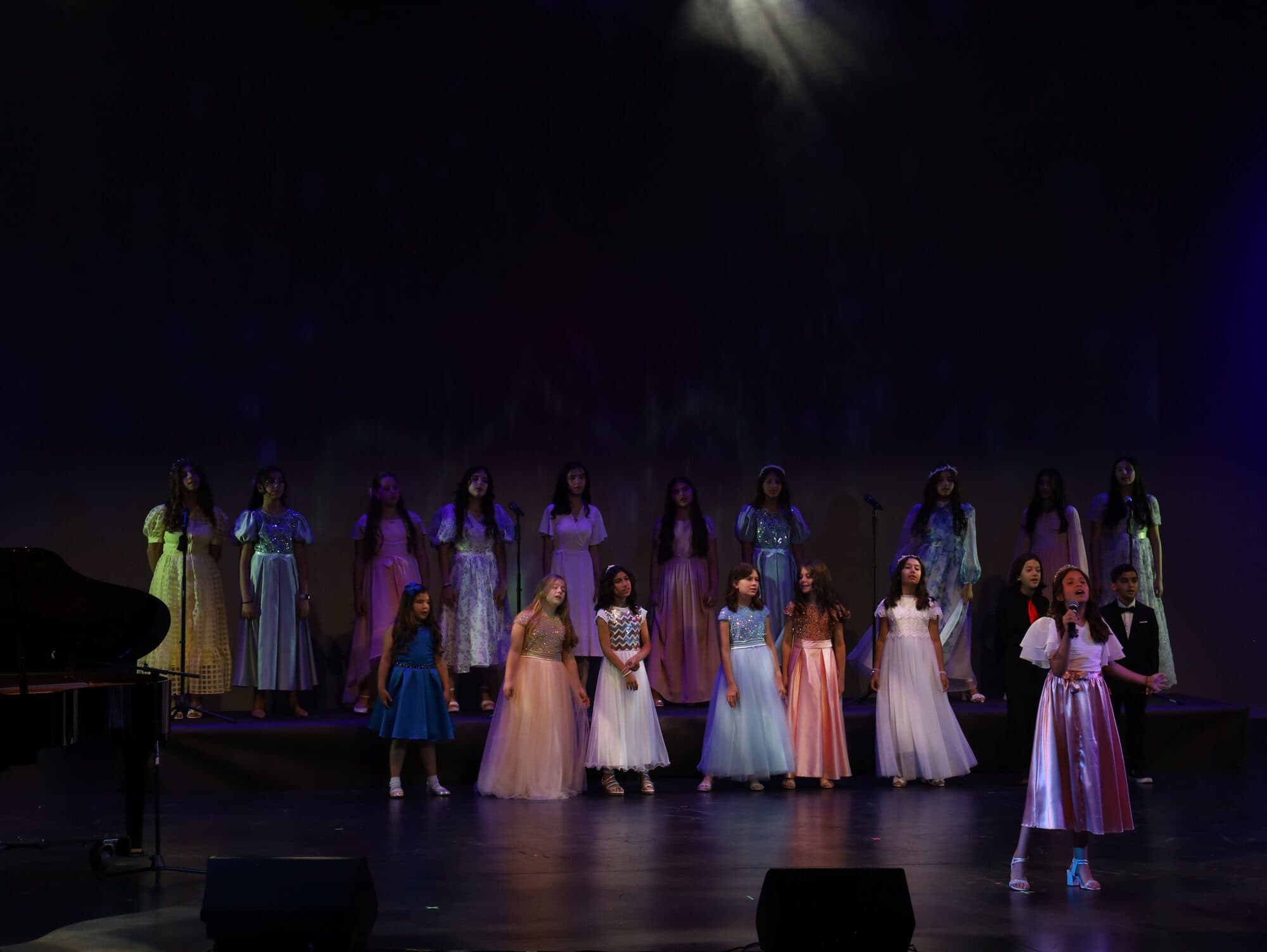 Dozens of young performers in colourful dresses and costumes line the stage for the finale